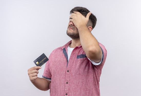 Homem preocupado segurando um cartão de crédito